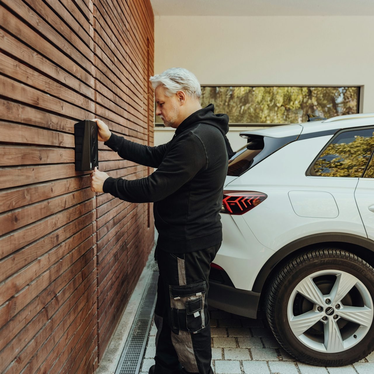 Installer fitting an electric vehicle (EV) charger to a residential home’s exterior wall.