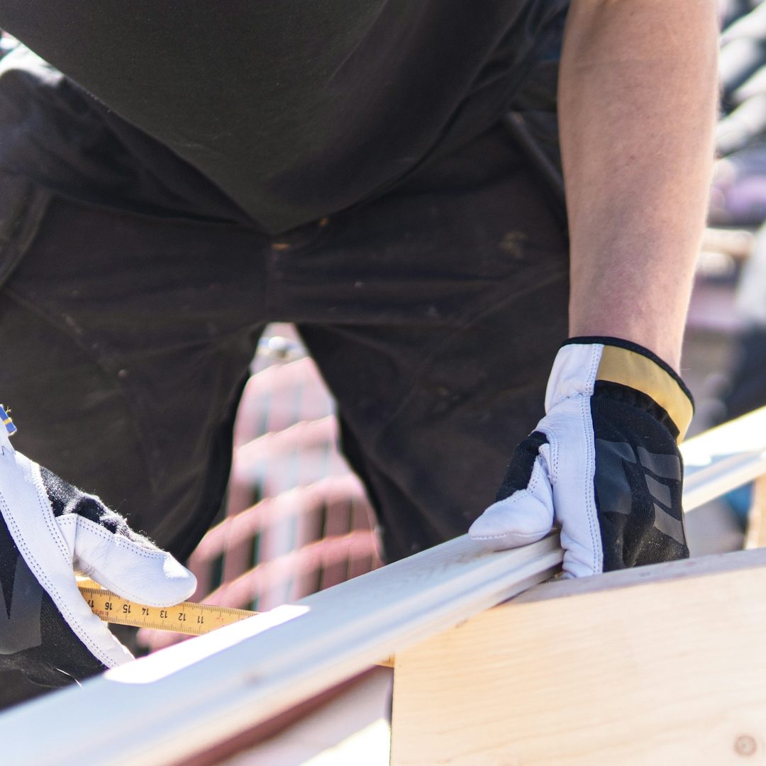 Workman measuring dimensions for a construction project with a tape measure.