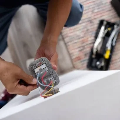 A man is troubleshooting electrical equipment, demonstrating technical skills in a professional environment.